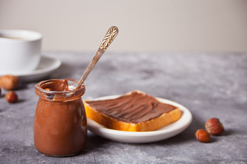 Bread toast with chocolate cream butter, jar of chocolate cream on the concrete background