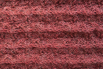A close up of knitted woolen texture of coral color. Hand made.
