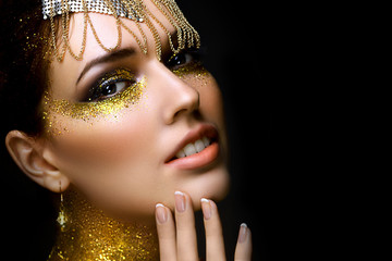 Beautiful woman portrait with golden glitter on her face. Girl with art make-up with golden sparkles. Fashion model with golden makeup