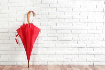 Beautiful red umbrella near white brick wall. Space for text