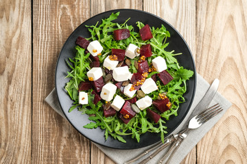 Salad with beetroot, feta cheese, arugula and spicy dressing on a rustic background top view. Healthy food. Top view. Copy space.