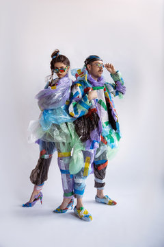 Woman and man wearing plastic on white background. Models in clothes and shoes made of garbage. Fashion, style, recycling, eco and environmental concept. Too much pollution, we're eating and taking it