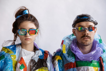 Woman and man wearing plastic on white background. Models in clothes and shoes made of garbage. Fashion, style, recycling, eco and environmental concept. Too much pollution, we're eating and taking it