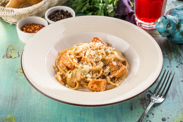 Italian pasta with zucchini, chicken and Parmesan cheese on blue wooden table