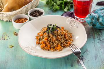 Tasty Pearl barley porridge with carrot and glass of red drink on blue wooden table