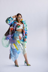 Woman wearing plastic on white background. Female model in clothes and shoes made of garbage. Fashion, style, recycling, eco and environmental concept. Too much pollution, we're eating and taking it.