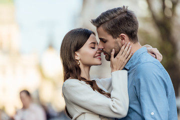 Fototapeta premium happy girl with closed eyes kissing handsome boyfriend on street