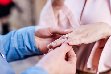 Fototapeta na wymiar cropped view of man putting wedding ring on finger of girlfriend