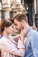 young couple of tourists embracing with closed eyes while standing on street