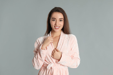 Obraz premium Beautiful young woman in bathrobe on grey background