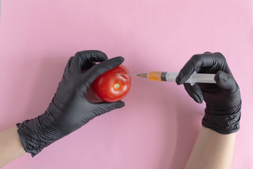 Chemical processing of vegetables, fertilizers and GMOs. Hand of person injects chemicals into...
