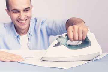 Man ironing clean shirt, husband happy to do housework, close up, toned