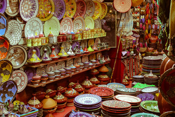 Colorful Moroccan ceramics and pottery displayed with typical slippers in the background in a shop in the Souks in the Medina of Marrakech, Morocco