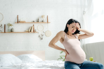 beautiful exhausted pregnant girl having headache in bedroom