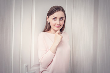 Fototapeta premium Sly girl hiding behind the door, woman playing hide and seek, portrait, toned