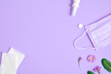Workspace with napkins, pills, face mask, drops bottle and flowers on purple background. Creative flat lay concept of seasonal spring and summer pollen allergy. Top view, copy space, minimal style
