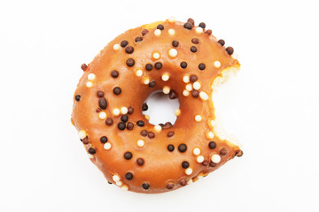 Bitten brown donut with bright sprinkles, white background, top view