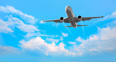 Naklejka premium White passenger airplane in the clouds - Travel by air transport