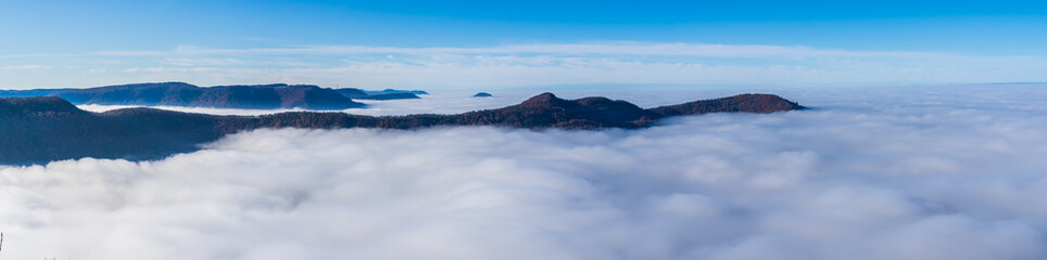 Germany, XXL panoramaaerial  view above endless sea of fog clouds in valley of swabian jura nature landscape on sunny day with blue sky near stuttgart