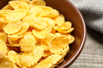 Tasty crispy corn flakes in bowl, closeup