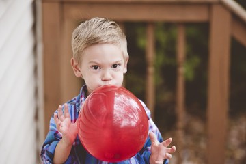Closeup shot of a child blowing up a balloon with a blurred background