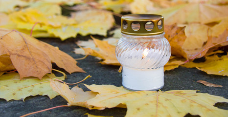 Monument and candles in the cemetery. All Saints Day in Poland. Candle in the cemetery. Candle in the yellow leaves.