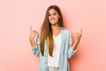 Young slim woman indicates with both fore fingers up showing a blank space.