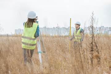 Surveyors working with digital level and ruler in field