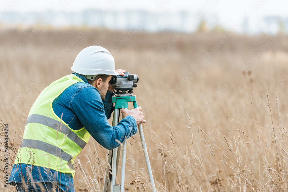 Wall mural Surveyor with digital level working in field