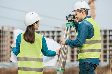 Surveyors working with blueprint and digital level