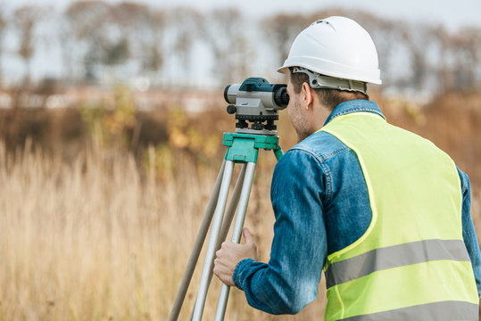 Surveyor looking through digital level in field