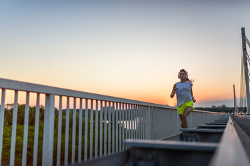 Fototapeta premium jogging, fitness, girl, run, woman, bridge, sunset, athlete, workout, beautiful, young, healthy, exercise, lifestyle, runner, female, fit, sport, outdoor, training, city, person, outside, jogger, wome