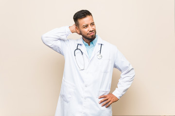 Young south-asian doctor man touching back of head, thinking and making a choice.