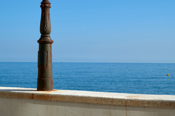 Fototapeta na wymiar Muro y farola frente al mar en un día soleado