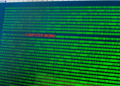 Red inscription Computer worm in malicious computer code written by a hacker. Picture of a computer screen with a dangerous program code.
