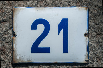 Weathered grunge square metal enameled plate of number of street address with number 21 closeup