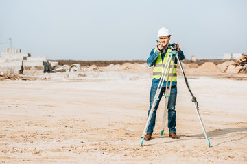 Surveyor with digital level talking on radio set on dirt road