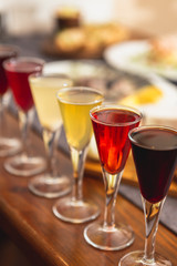 many glasses of shot or liqueur. Friends drink shot or liqueur and cheers. alcohol on blurred table background. Party and toast concept.