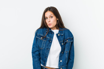 Young cute woman shrugs shoulders and open eyes confused.