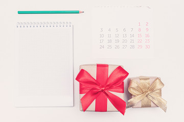 Calendar, pencil, notebook, gift with red ribbon, white desktop, copy space, for recording, close up, top view