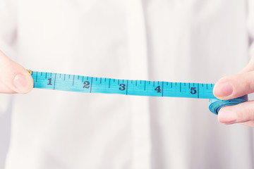 Girl with measuring tape shows 5 inch length, female hand, close up, cropped image, toned