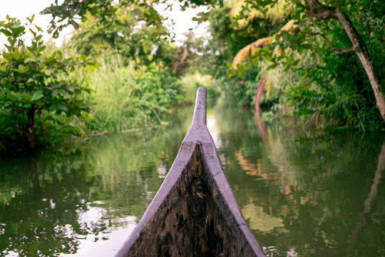 riding wood fishing boat in kerala backwaters village water channel under palm trees, a pristine natural environment during monsoon season