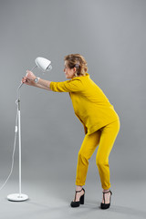 girl in the studio in a yellow suit, gray background, lamp floor lamp