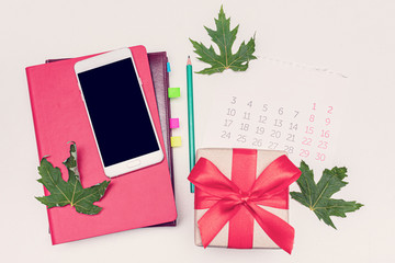 Smart phone and fallen leaves, gift, calendar, notebook, pencil, top view