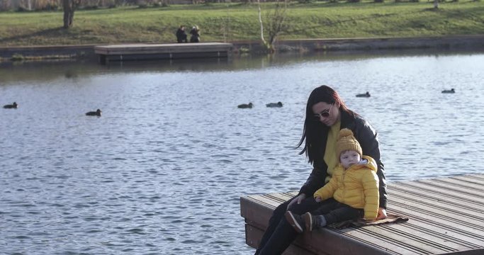 Mom with a baby feed ducks