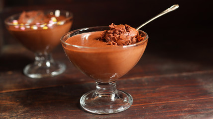 Chocolate mousse in transparent bowls on the old dark brown table background