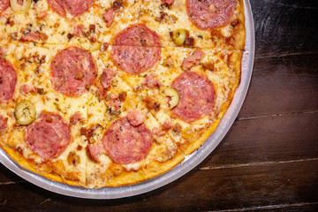 Homemade hot pepperoni pizza ready to eat on a wooden table and aluminum tray