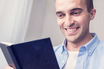 Student reads a book, guy smiling, portrait, close up, toned