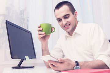 Man uses smartphone, man working in the office, break from work, front view, toned