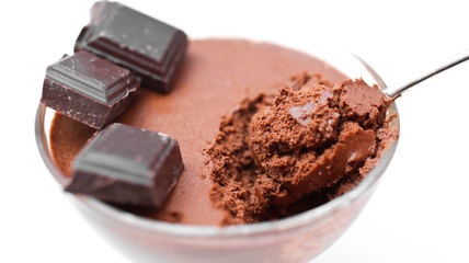 Chocolate mousse and pieces of chocolate in a transparent bowl on a white background